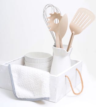 A chic arrangement of white kitchen utensils and decor in a rustic tray for modern elegance.