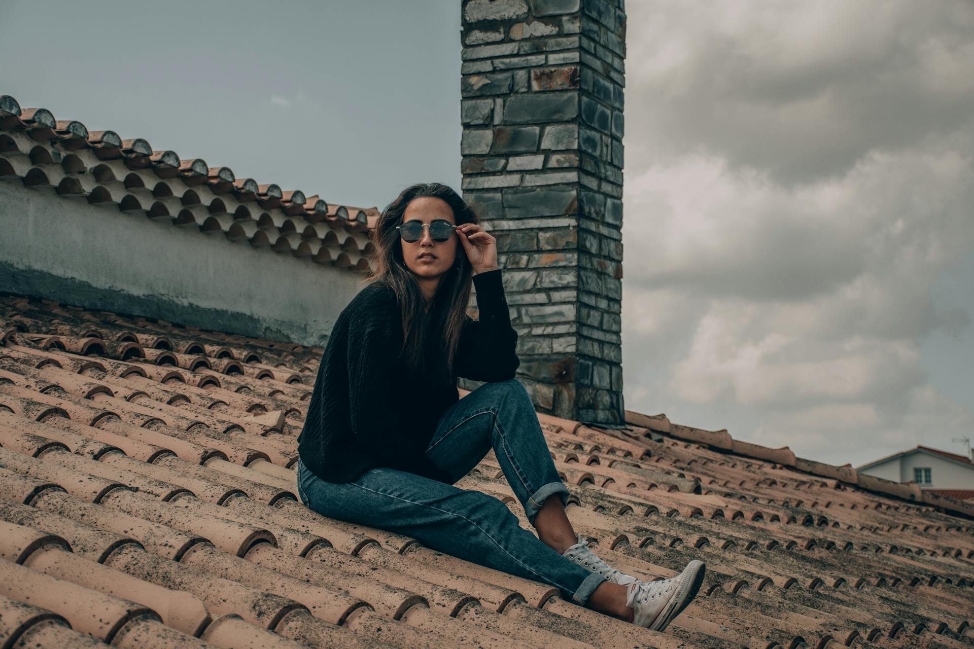 Woman in Black Top and Denim Jeans Sitting on Roof