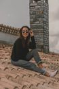 A Happy Woman in Sunglasses Sitting on a Roof
