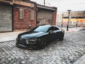 一辆光滑的黑色汽车停在城市中一条以砖砌建筑为特色的鹅卵石街道上