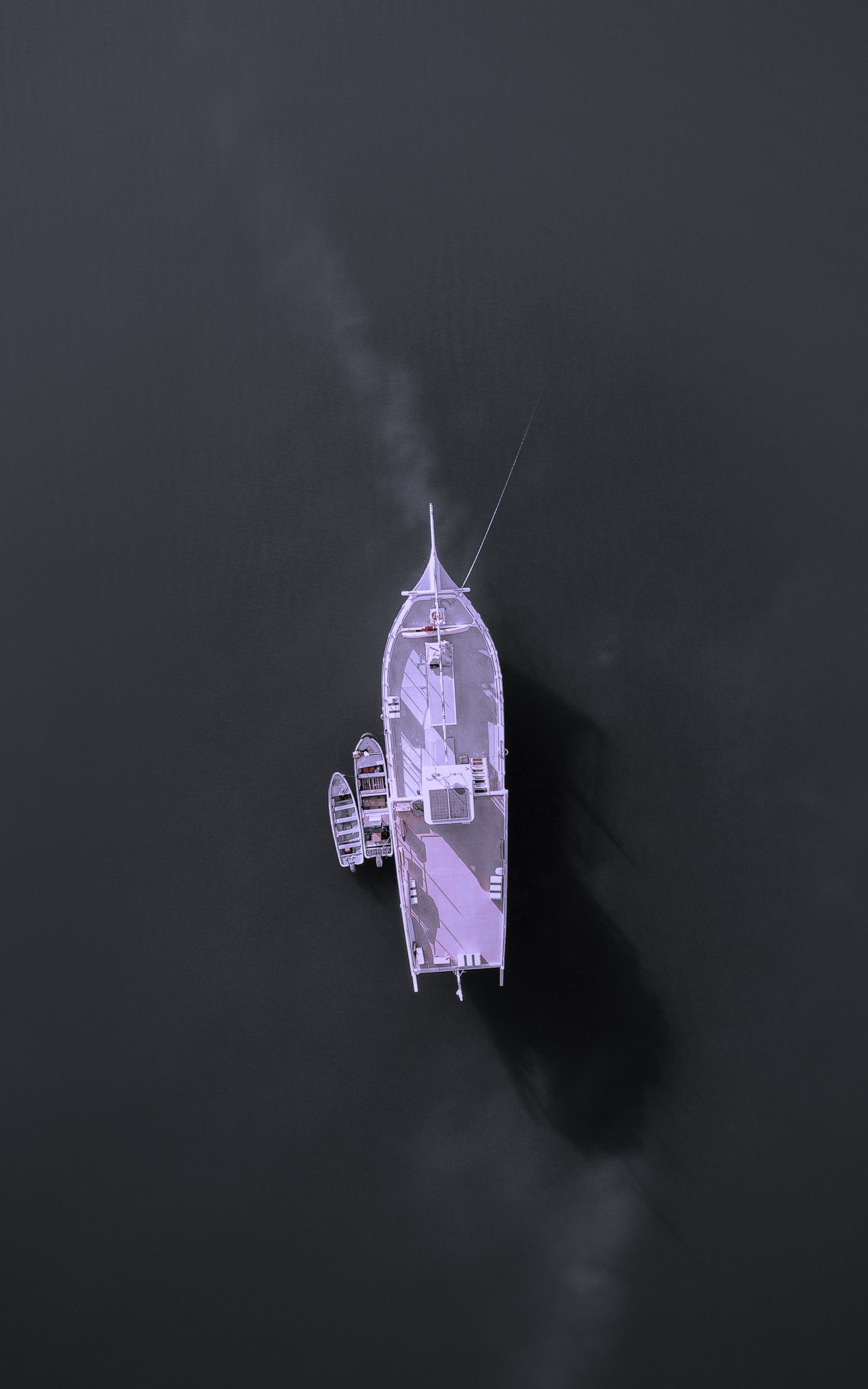 A serene aerial shot of a boat gliding through tranquil waters in Oman. Ideal for travel and nature themes.