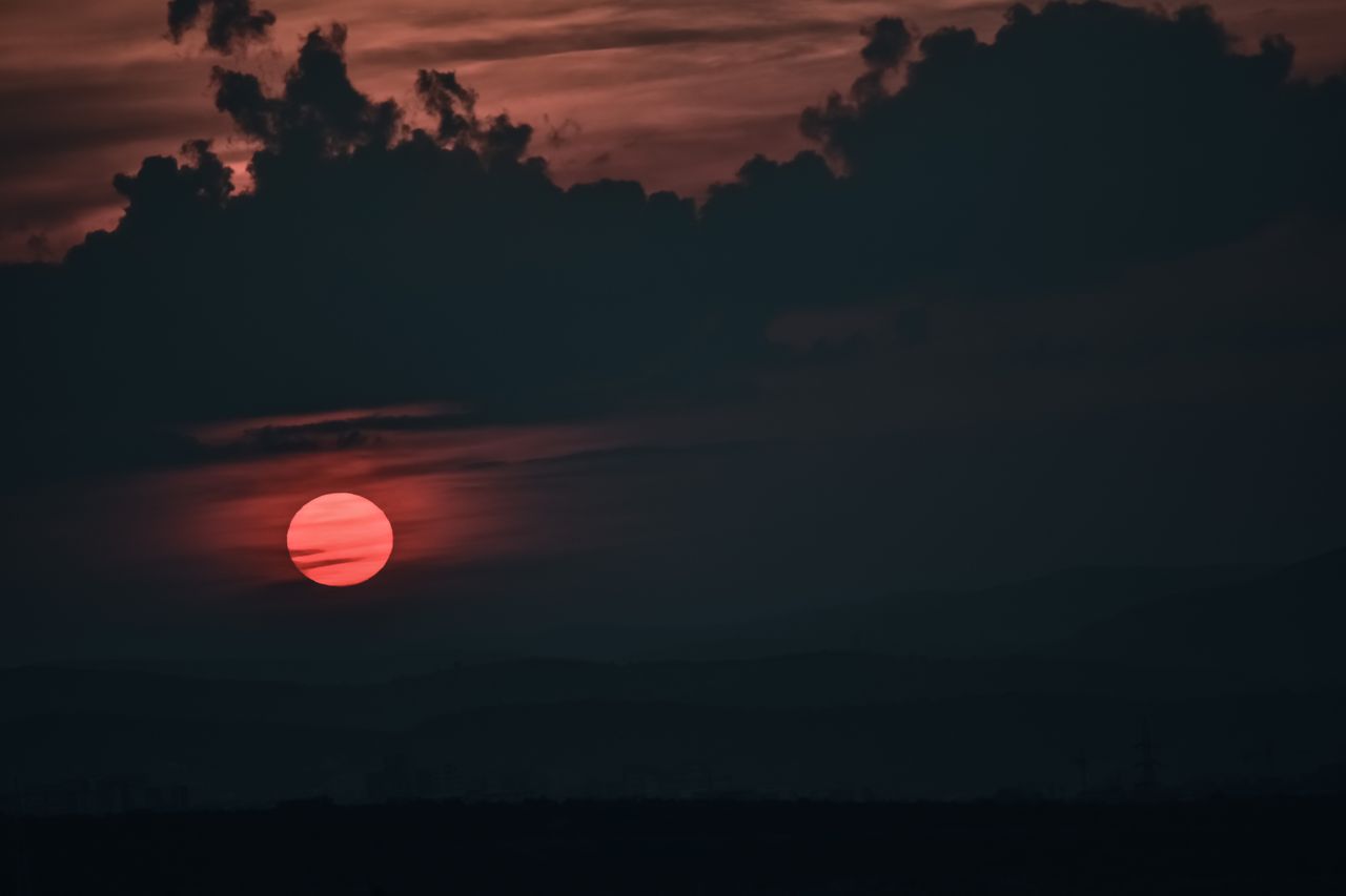 a captivating sunset with red skies and silhouetted clouds over a sere