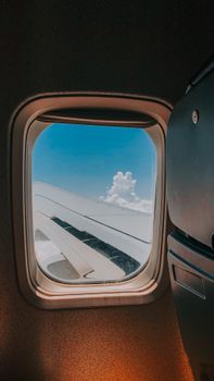 Scenic airplane wing view with fluffy clouds and blue sky from the window.
