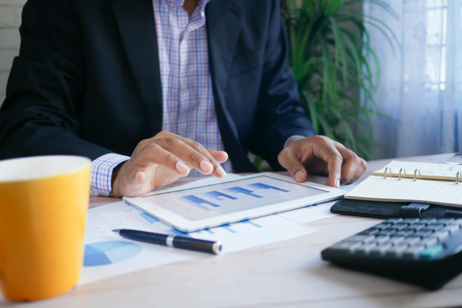 Man in office analyzing financial data on a digital tablet.