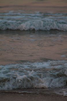 Captivating scene of ocean waves crashing on the beach at sunset, showcasing nature's beauty.