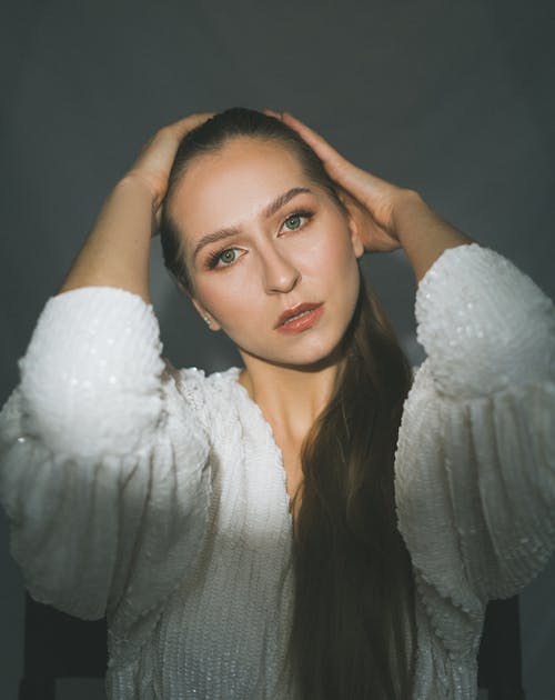 A Woman in White Long Sleeves with Her Hands on Her Head