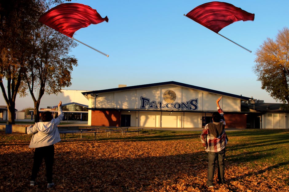 Children practicing flag waving on school grounds during autumn.