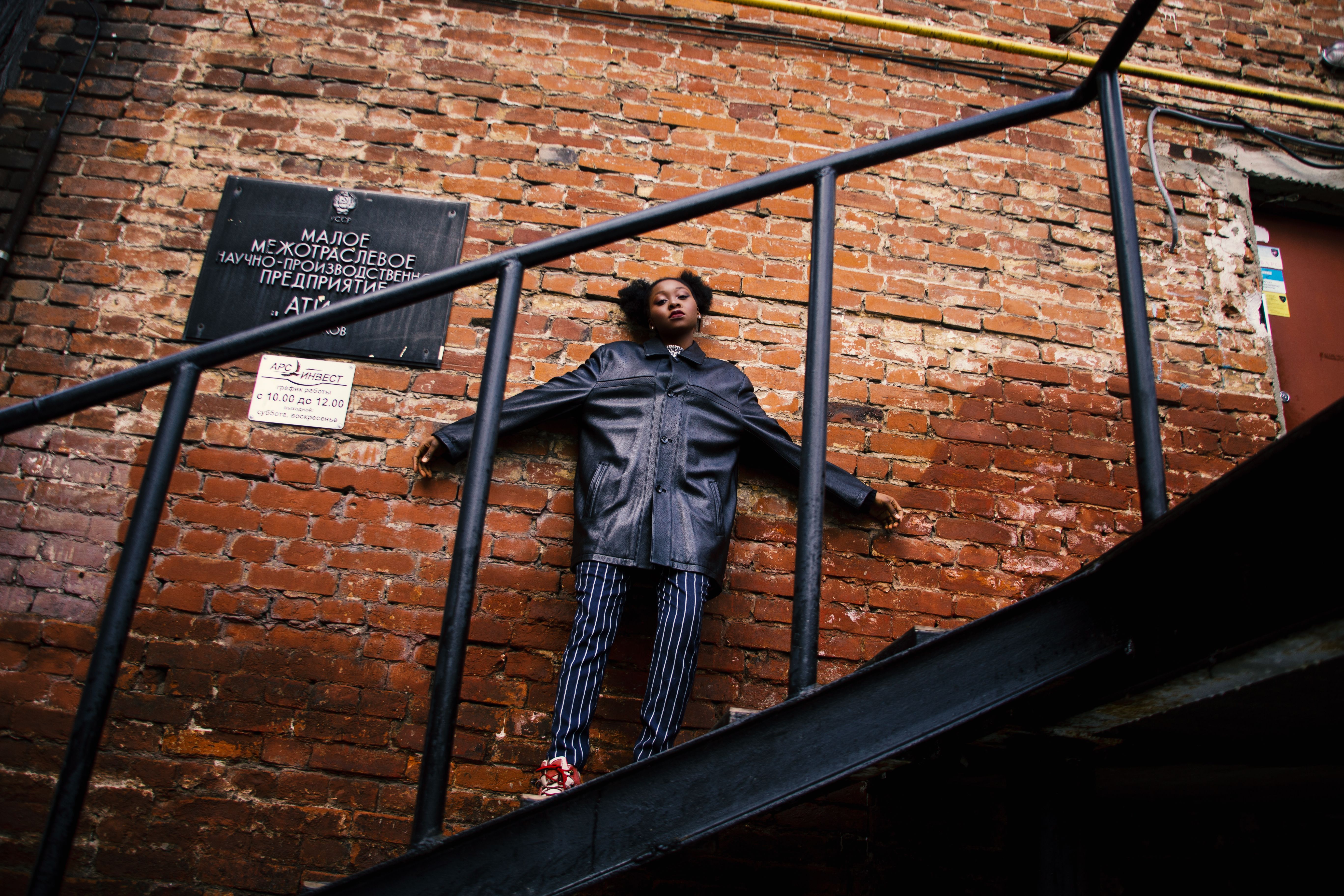 Woman in Black Jacket Standing on the Stairs · Free Stock Photo