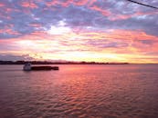 日落时分，渔船宁静的景象与充满活力的天空倒映在大海上