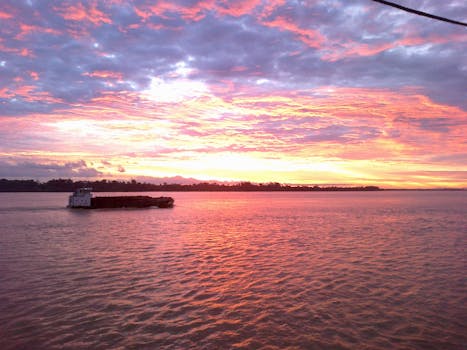 日落时分，渔船宁静的景象与充满活力的天空倒映在大海上