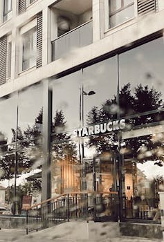 Contemporary Starbucks facade showcasing glass windows and exterior reflections on a rainy day.