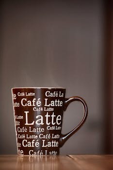 一杯热气腾腾的拿铁咖啡特写，杯身覆盖着醒目的文字，非常适合舒适的早晨