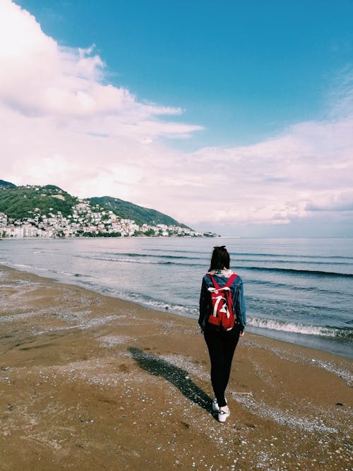 Free A Woman Carrying a Backpack at the Beach   Stock Photo