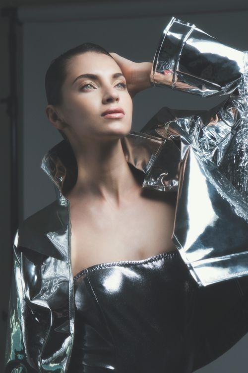 Free Elegant portrait of a woman in a metallic silver outfit, against a studio backdrop. Stock Photo