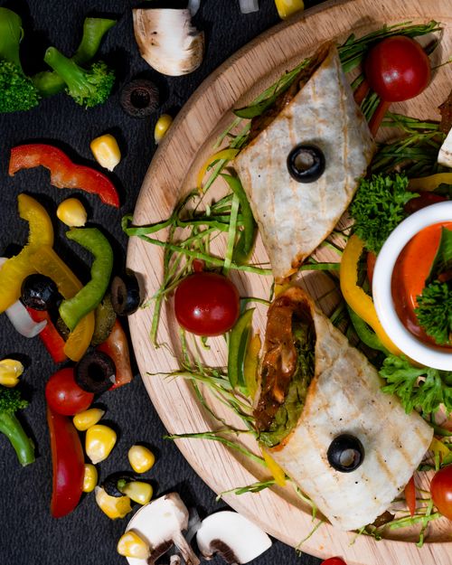 Free A vibrant flat lay of a vegetable wrap surrounded by fresh ingredients on a rustic wooden board. Stock Photo