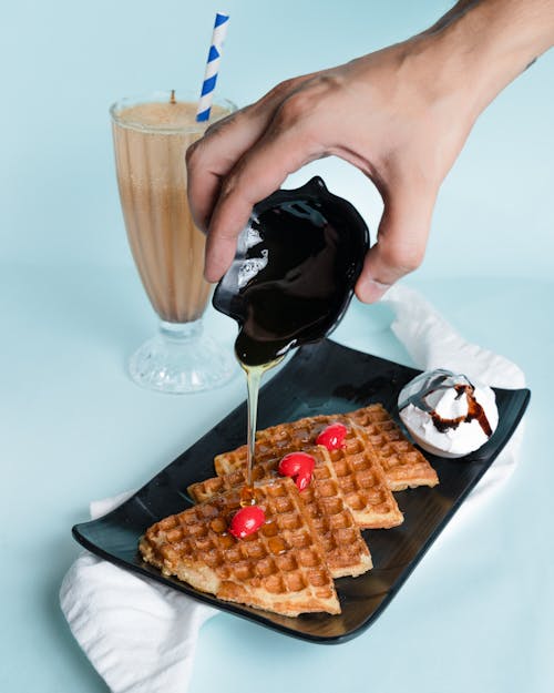 Free A Person Pouring Syrup on a Waffle Stock Photo