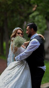 A bride and groom share a romantic dance outdoors, surrounded by lush greenery.