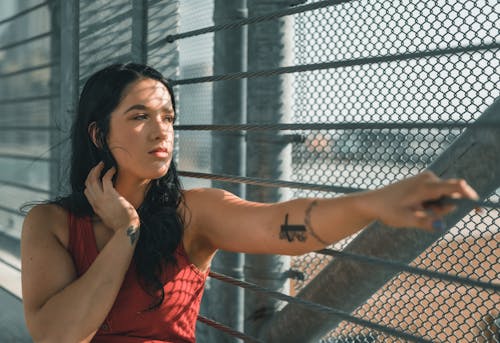 A Woman in Red Tank Top Looking at the Metal Fence with Railings