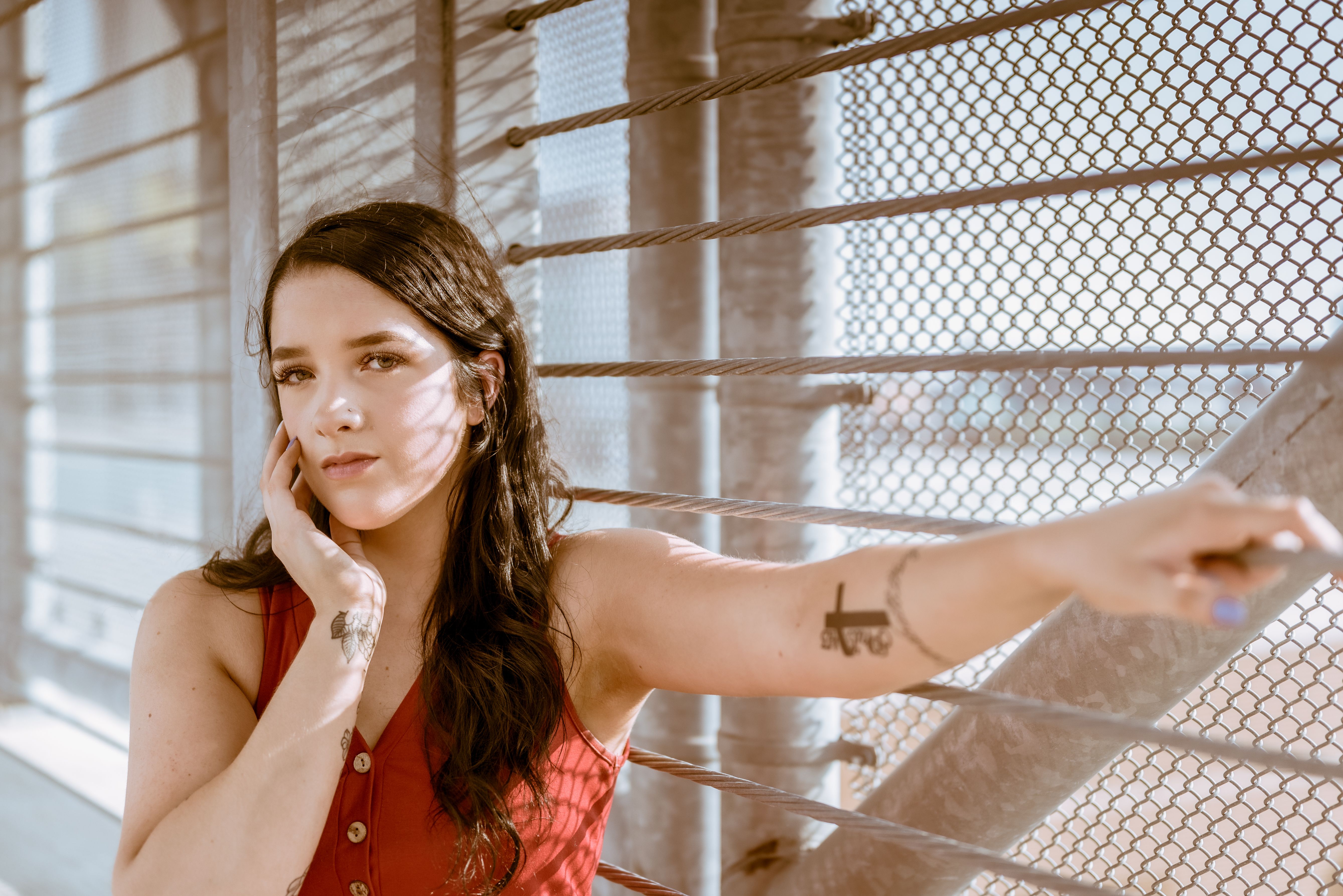 Woman in Red Sleeveless Top Leaning on Metal Fence · Free Stock Photo
