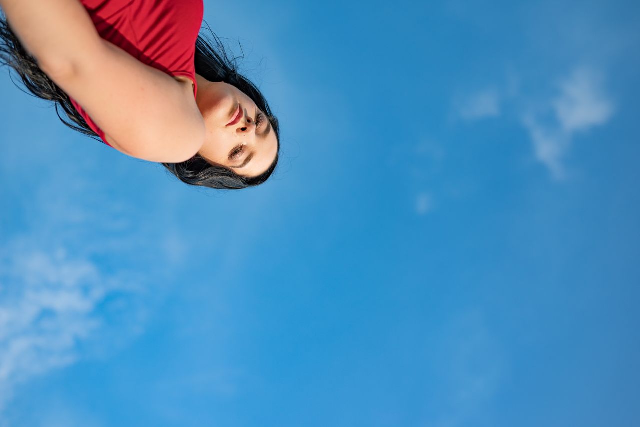 artistic low angle shot of a woman in red with a vivid blue sky backdr