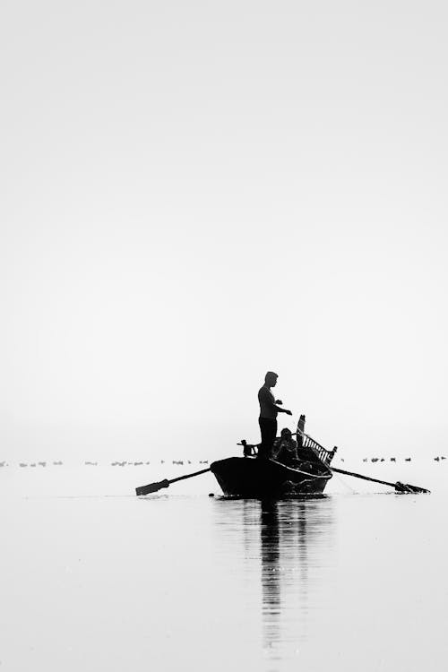Free Moncohrome Photo of Fisherman Standing on Boat Stock Photo