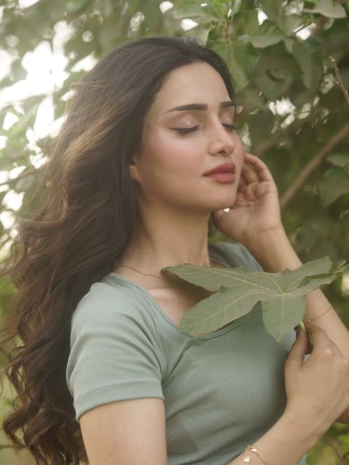 Free Portrait of a woman with closed eyes holding a leaf, enjoying nature. Stock Photo
