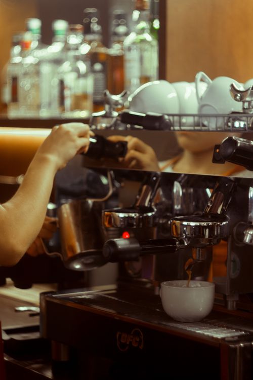 Free A barista using an espresso machine to make coffee in a warm, cozy cafe environment. Stock Photo