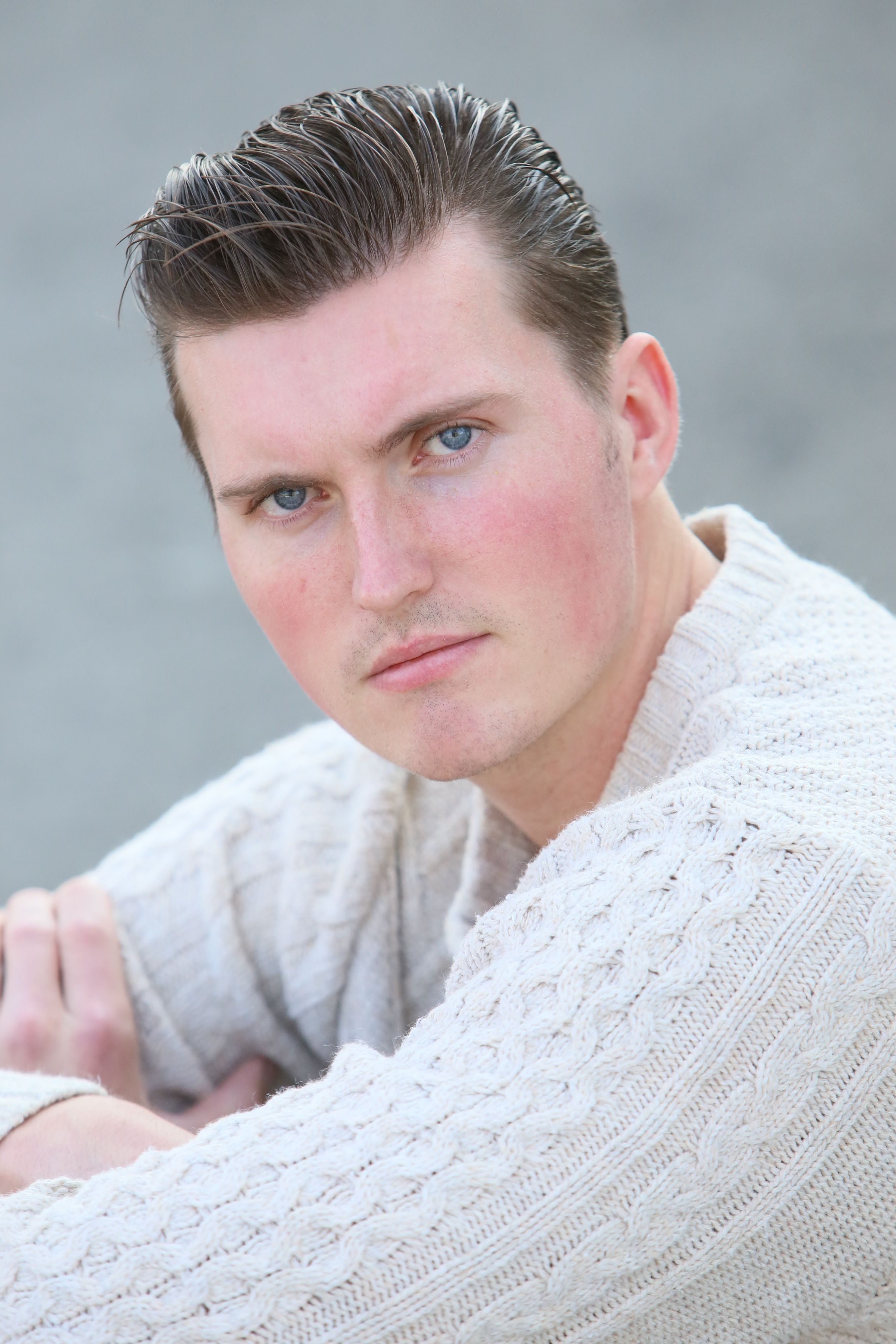 A close-up portrait of a man in a knitted sweater, showcasing a confident pose.