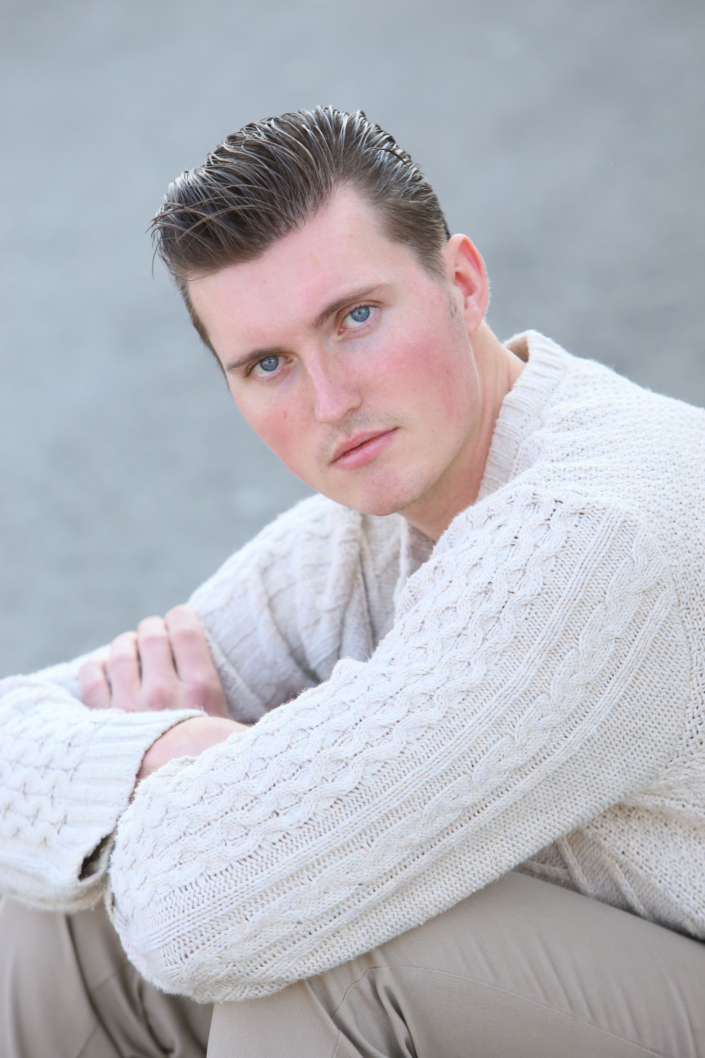 A thoughtful man wearing a knitted sweater posing outdoors, perfect for lifestyle and fashion themes.