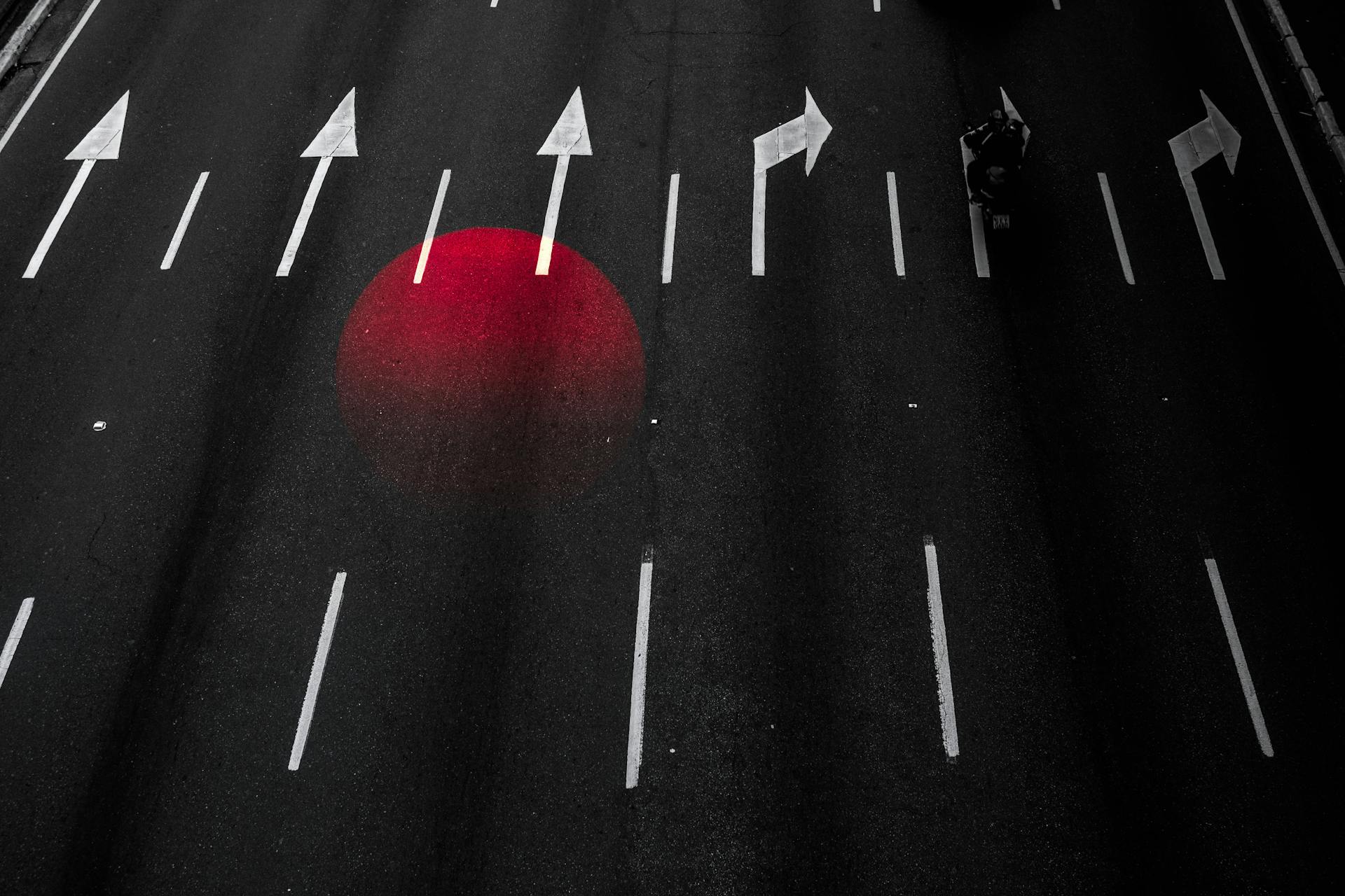 A conceptual asphalt road with directional arrows and red light reflection, symbolizing guidance and minimalism.