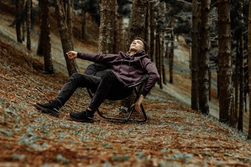 Free Young Man Sitting in the Folding Chair in Woods Stock Photo