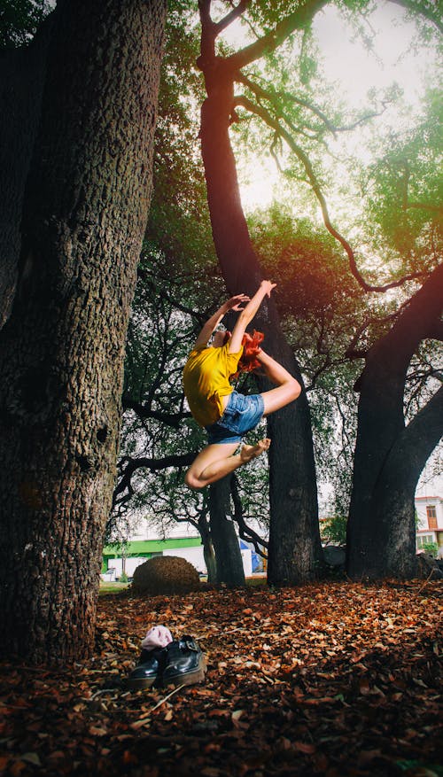 Free Person in Yellow Shirt and Blue Denim Shorts Doing Ballet Stance on Woods Stock Photo