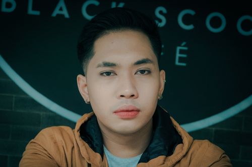 Free Serene portrait of a young man with earrings, captured indoors. Stock Photo