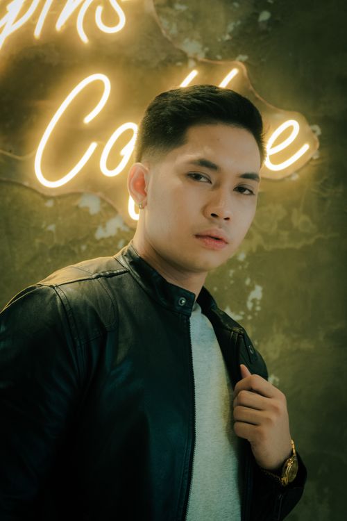 Free Modern portrait of a young man in a leather jacket, standing confidently by neon lights. Stock Photo