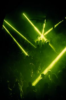 Dynamic crowd scene with vibrant green laser lights at a nightclub party.