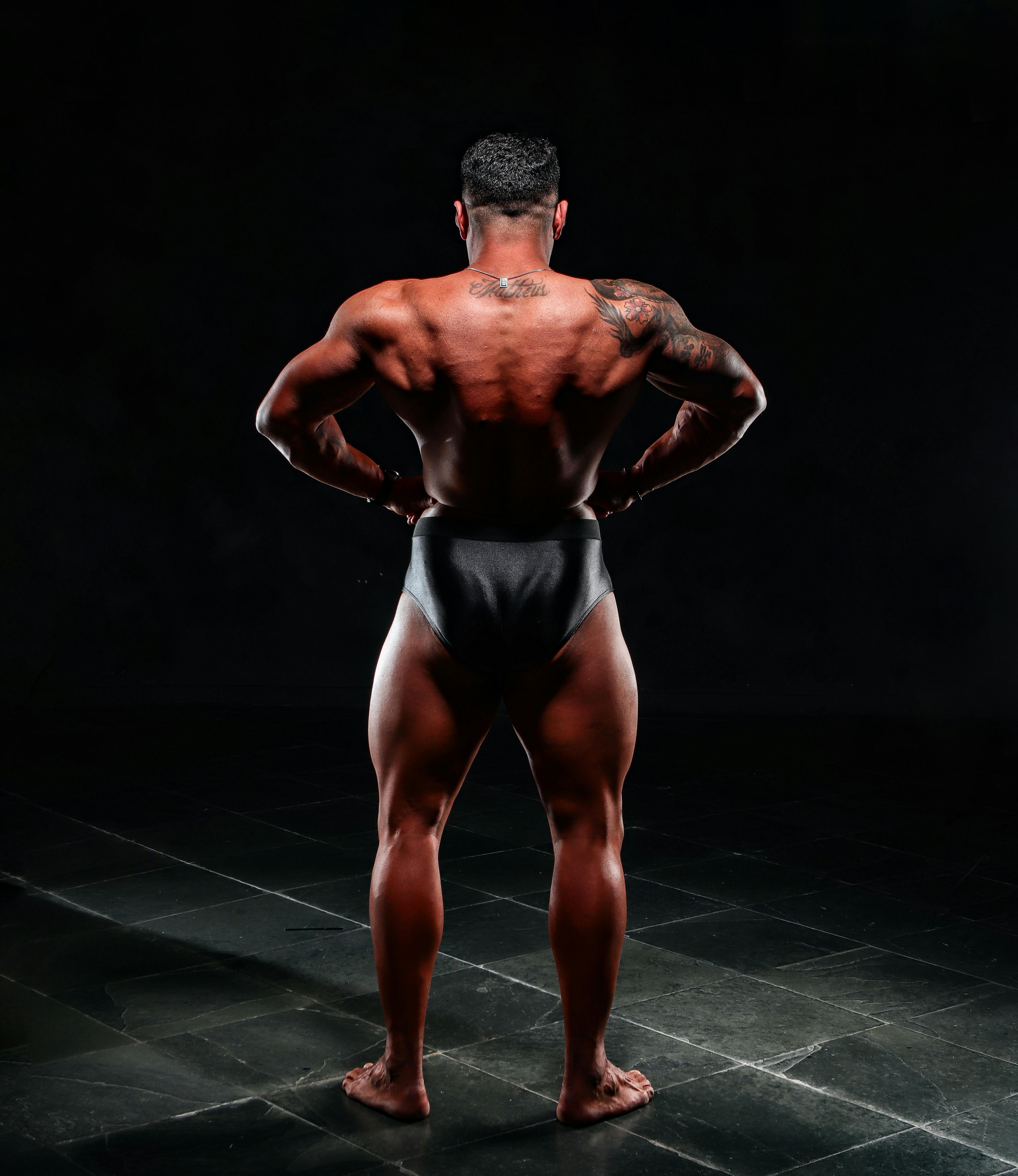 Back double biceps pose by brutal caucasian bodybuilder on grunge  background Stock Photo | Adobe Stock