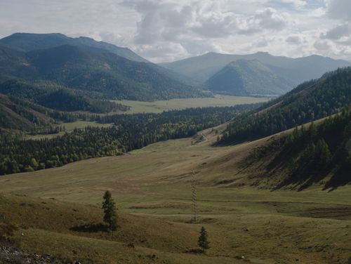 Free Peaceful view of a lush green mountain valley under a cloudy sky. Stock Photo