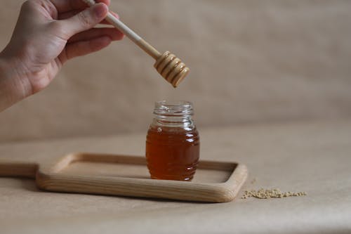 A Hand Holding a Honey Dipper 