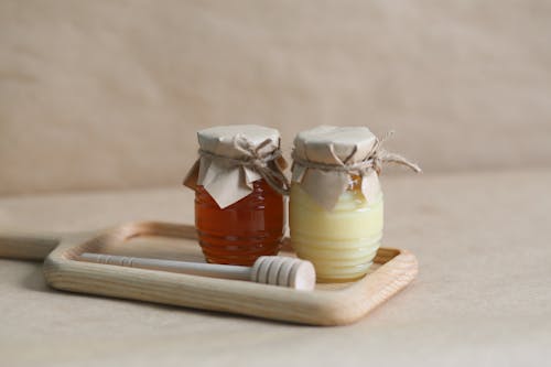 Glass Jars and a Honey Dipper on a Wooden Tray