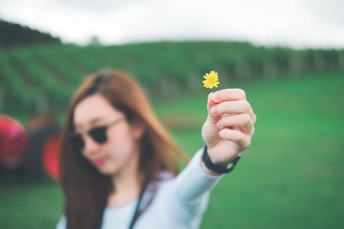 Женщина, держащая желтый цветок с лепестками