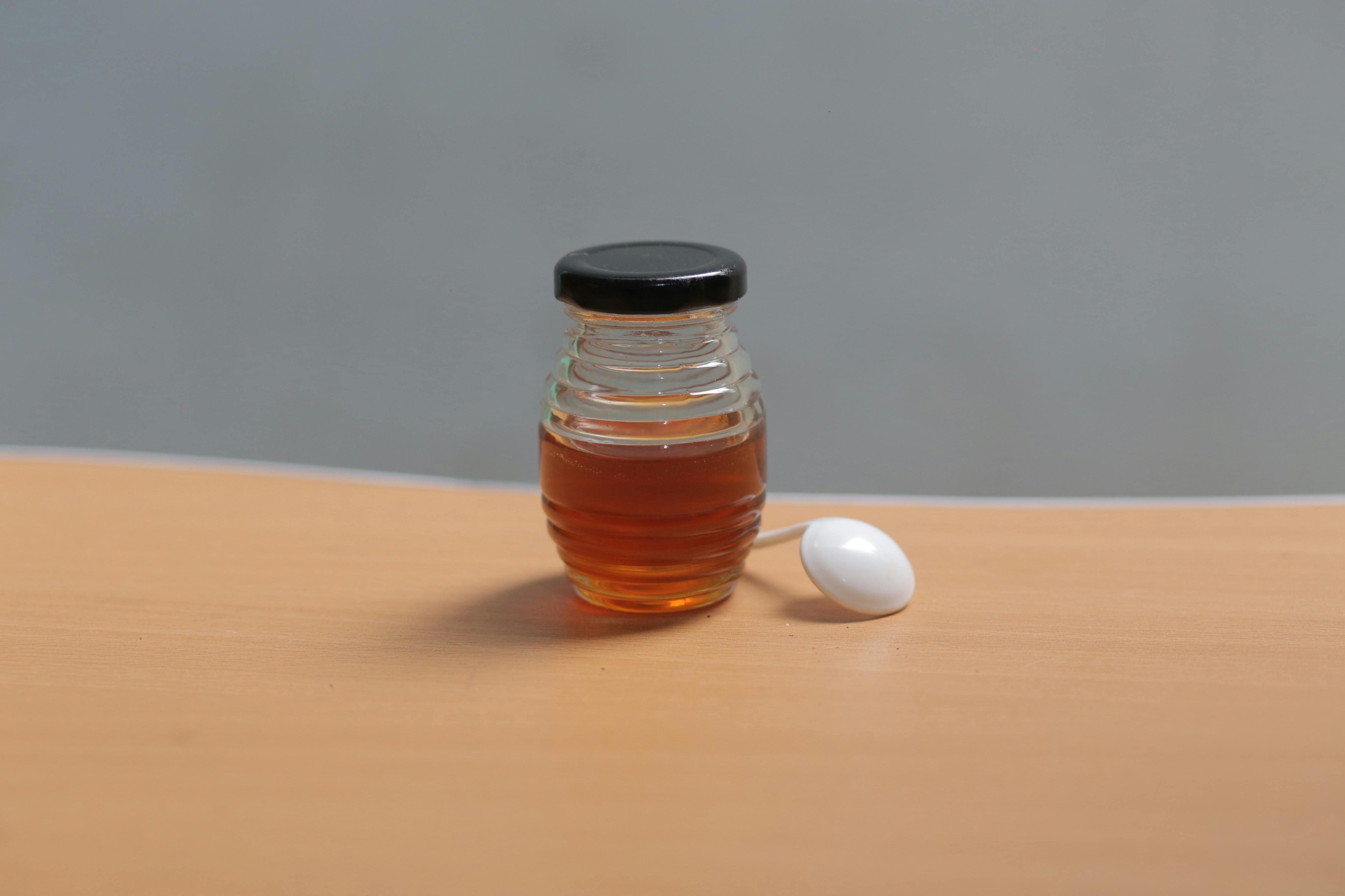 Graficzne przedstawienie jednorazowego e-papierosa z etykietą Honey Peach, obok świeżych brzoskwiń i słoiczka miodu, na tle delikatnego dymu.