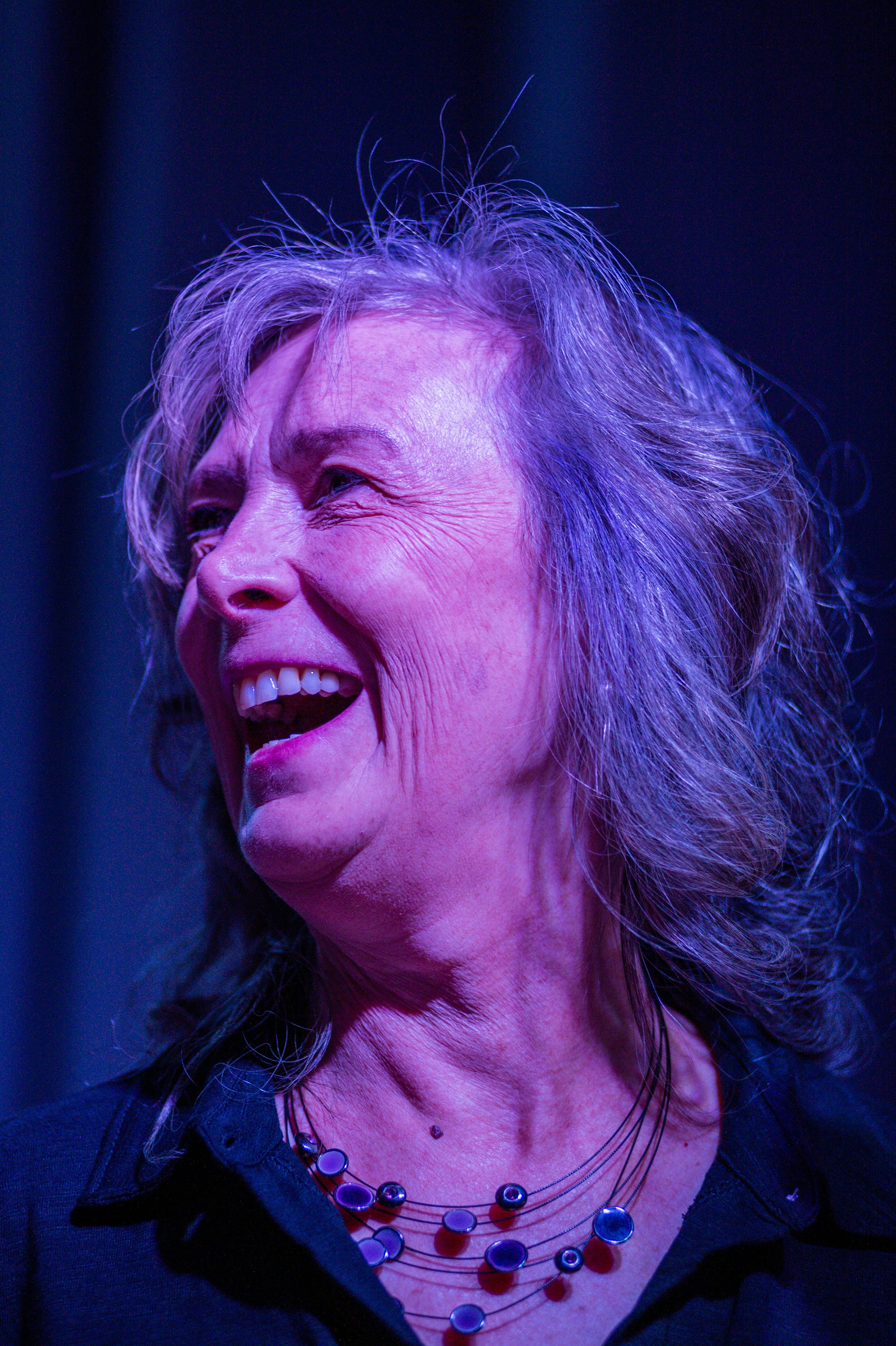 A senior woman joyfully laughing, captured with vivid lighting in a close-up shot.