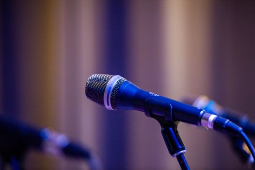 Close-up of a professional microphone on stage with blurred bokeh background.