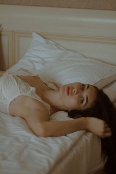 A serene portrait of a woman in lingerie lying on a bed, exuding elegance and calmness.