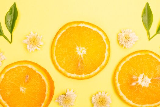 Bright and fresh orange slices with flowers on a yellow background.