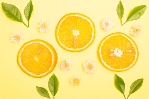 Sliced Orange Fruit and Flowers on a Yellow Surface