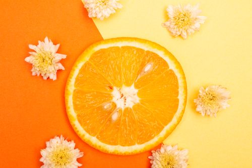 Free Vibrant sliced orange on orange and yellow background with flowers. Stock Photo