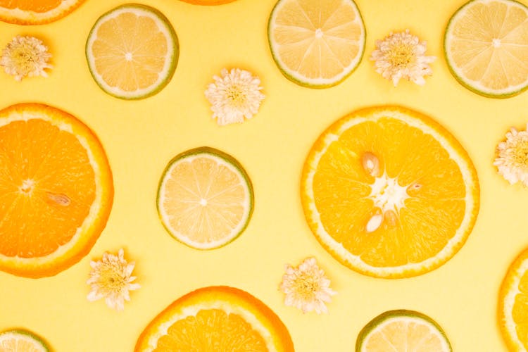 Slices Of Oranges And Limes On A Yellow Background