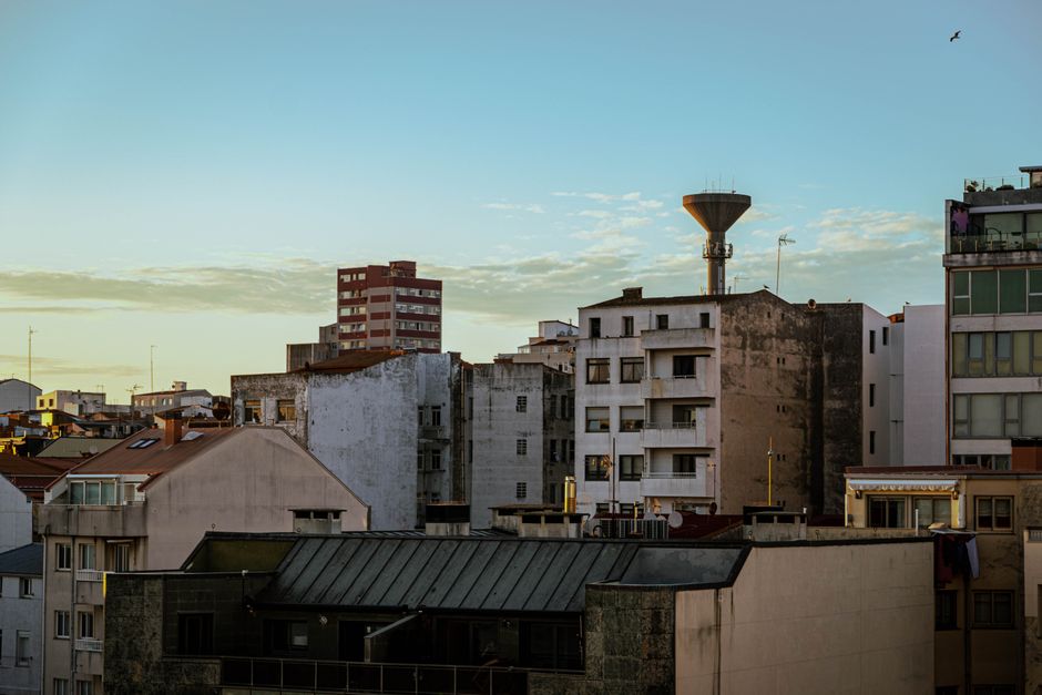 Vista escénica de edificios residenciales al atardecer en A Coruña, España, con la silueta de un tanque de agua.