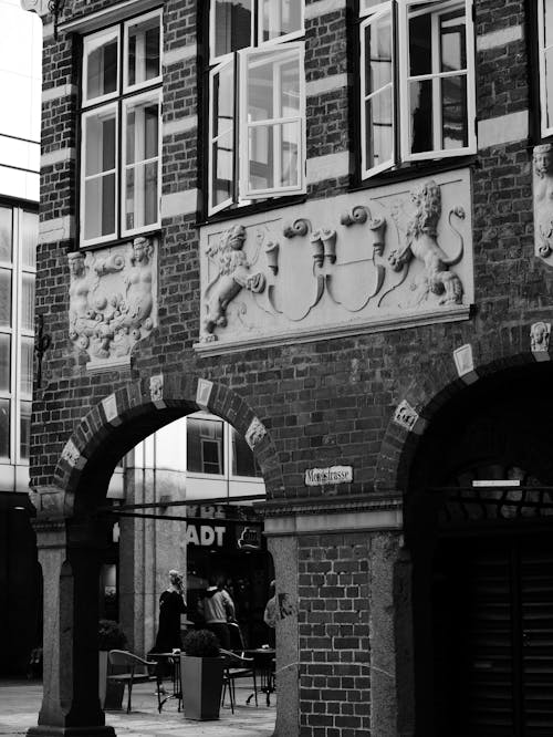 A Grayscale of a Brick Building with Wall Sculptures